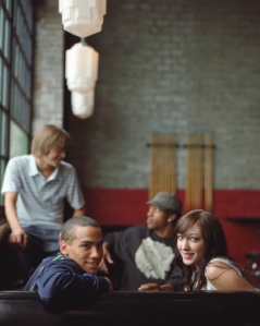 Four young adults sitting in booth (focus on couple in foreground)